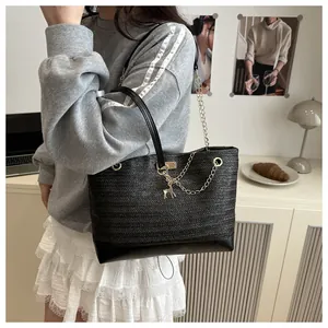 Détail du sac cabas tissé noir avec bandoulière chaîne dorée et pendentif cerf