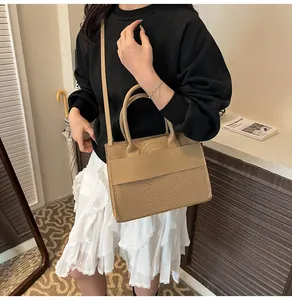 Dettaglio della borsa tote kaki effetto serpente indossata con un look moderno