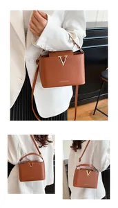 Detailed view of caramel brown leather bucket bag with gold V hardware and strap
