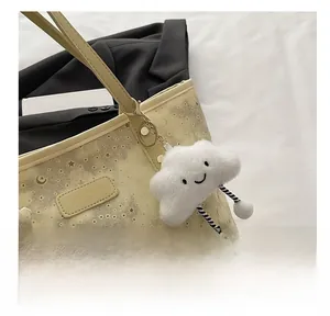 Close-up of white plush cloud charm with embroidery on a pale yellow designer tote bag