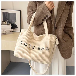 Detail of cream corduroy tote bag with black embroidery and adjustable shoulder strap