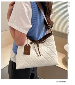 Close-up of white quilted square bag featuring a brown bow and fashion leather tag