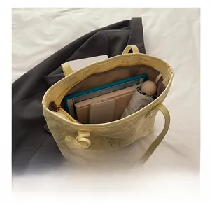Detail of yellow tote bag with star embroidery showing internal capacity for daily items