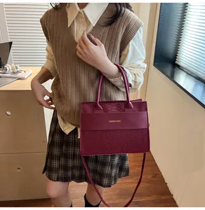 Dettaglio borsa tote bordeaux con motivo a coccodrillo e scritte dorate eleganti