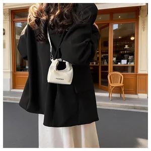 Mini white fashion handbag shown from the back with model wearing black blazer and skirt
