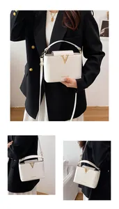 Detail of white PU leather crossbody bag with golden V-buckle and fashion lettering