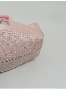 Detailed macro view of the reinforced thick base and woven leather texture on pink bucket bag