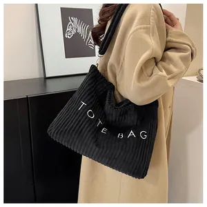 Detail of black corduroy tote bag with TOTE BAG embroidery and wide shoulder strap