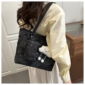 Detail of black tote bag with silver star moon print and plush cloud charm accessory