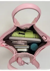Spacious interior of pink woven bucket bag showing umbrella, phone, and cosmetics