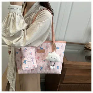 Dettaglio della borsa tote rosa a fiori con farfalle e ciondolo a nuvola di peluche