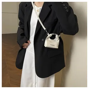 Close-up of a white mini fashion crossbody bag worn over a black oversize blazer