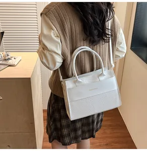 Dettaglio della borsa bianca in pelle coccodrillo con elegante scritta dorata per donna