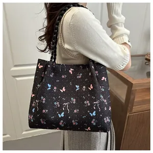 Detail of quilted tote bag featuring butterfly and bow patterns with woven handles