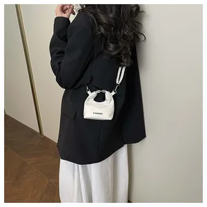 Detail showing white mini fashion handbag with metal handle and shoulder strap