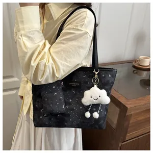 Detail of black star and moon pattern tote bag with white plush cloud charm and strap