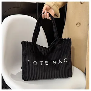 Detail of black corduroy tote bag with TOTE BAG print and textured finish on a chair