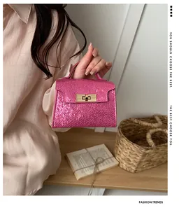 Detailed view of pink croc-embossed mini handbag with gold-tone twist lock closure