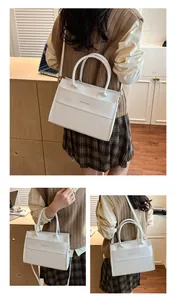 Close-up of white crocodile pattern tote bag featuring golden fashion text and sleek hardware