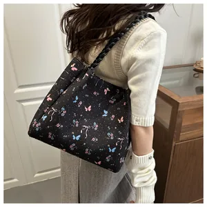 Close-up of black tote bag featuring colorful butterfly floral prints and twisted rope straps