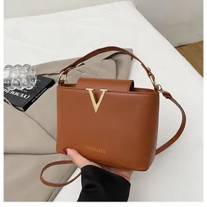 Close-up of caramel leather bucket bag with golden V logo and textured metal details