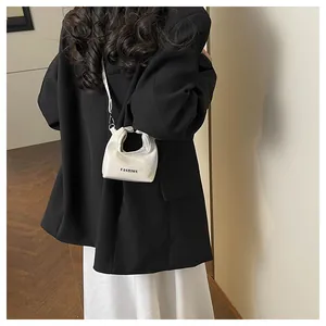 Mini white fashion bag with letter print shown as crossbody accessory on a model
