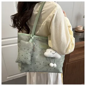 Detail view of mint green tote bag with star patterns and cloud charm accessory