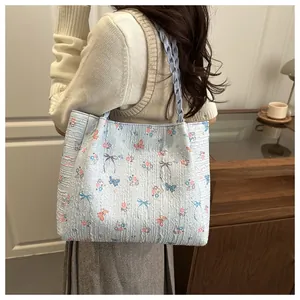 Detail view of large floral tote bag with blue woven shoulder straps and butterfly prints