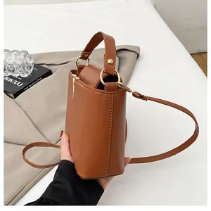 Detail of caramel leather bucket bag featuring gold metal rings and a wide top handle