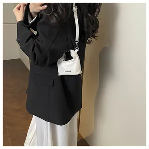 Close-up of white mini crossbody bag with FASHION text shown on a model