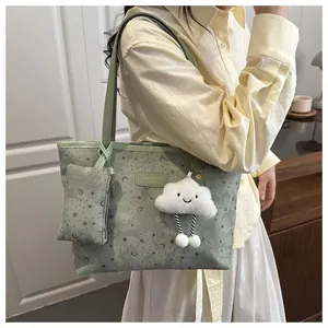 Close-up of light green embossed tote bag with cloud charm and matching mini pouch
