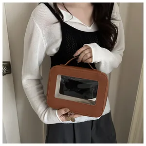 Détail de trousse de maquillage en cuir PU brun avec fenêtre PVC et zips dorés
