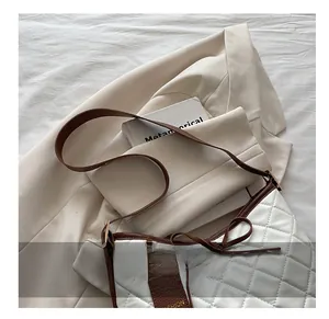 Detail of white quilted tote with brown leather handles and a decorative bow ornament