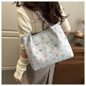 Detail of floral tote bag showing blue fabric with pink butterfly prints and woven strap