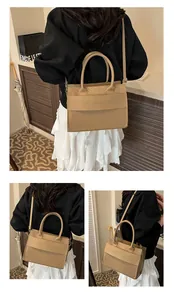 Detail of beige tote bag showing snake texture stitching and fashion typography