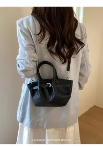 Elegant woman wearing black woven bucket bag with leather strap over her shoulder