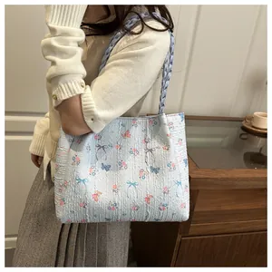 Detail of light blue floral tote bag with pleated texture and woven shoulder straps
