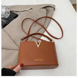 Detail of brown leather bucket bag featuring gold V-hardware and stylish crossbody strap