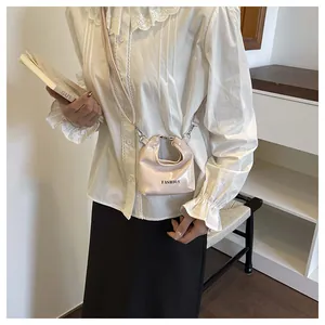 Close-up of pink patent leather mini bag with Fashion lettering on white lace outfit