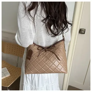 Detail shot of brown quilted tote bag showing diamond stitching and leather bow accent