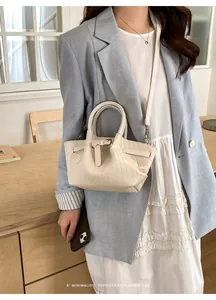Detail of cream woven bucket bag with leather buckle and handle in minimalist indoor setting