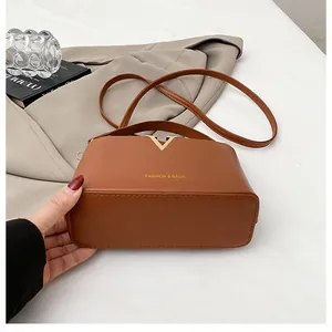 Detail of a brown PU leather bucket bag featuring a gold V-shaped metal buckle and strap