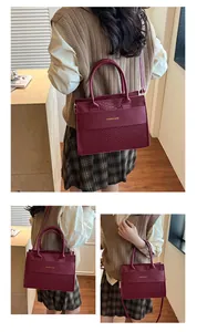 Detail view of burgundy tote bag with faux snake texture and adjustable strap on a model