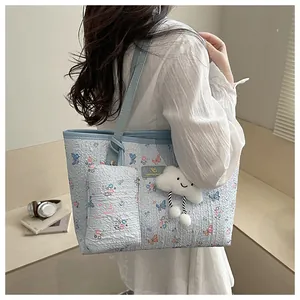 Borsa tote blu floreale con farfalle e ciondolo a nuvola mostrata nella vista laterale