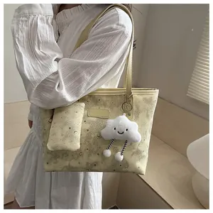 Detail view of the yellow tote bag with stars patterns and white cloud plush pendant