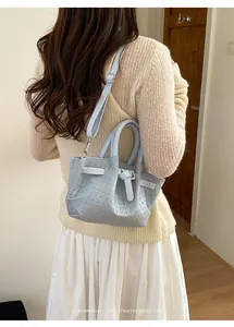 Detailed view of light blue woven bucket bag shown on model for elegant styling