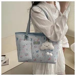 Dettaglio della borsa tote floreale azzurra con ciondolo a nuvola e mini borsa abbinata