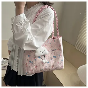 Detailed texture of pink floral tote bag with blue butterfly prints and cloud charm