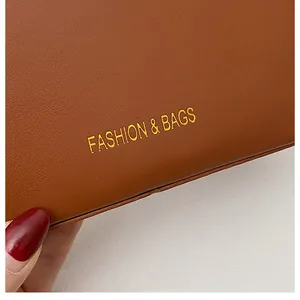 Macro detail of brown leather bucket bag with gold Fashion & Bags lettering