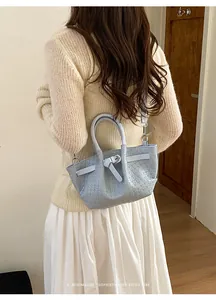 Close-up of light blue woven texture bucket bag styled with a minimalist outfit